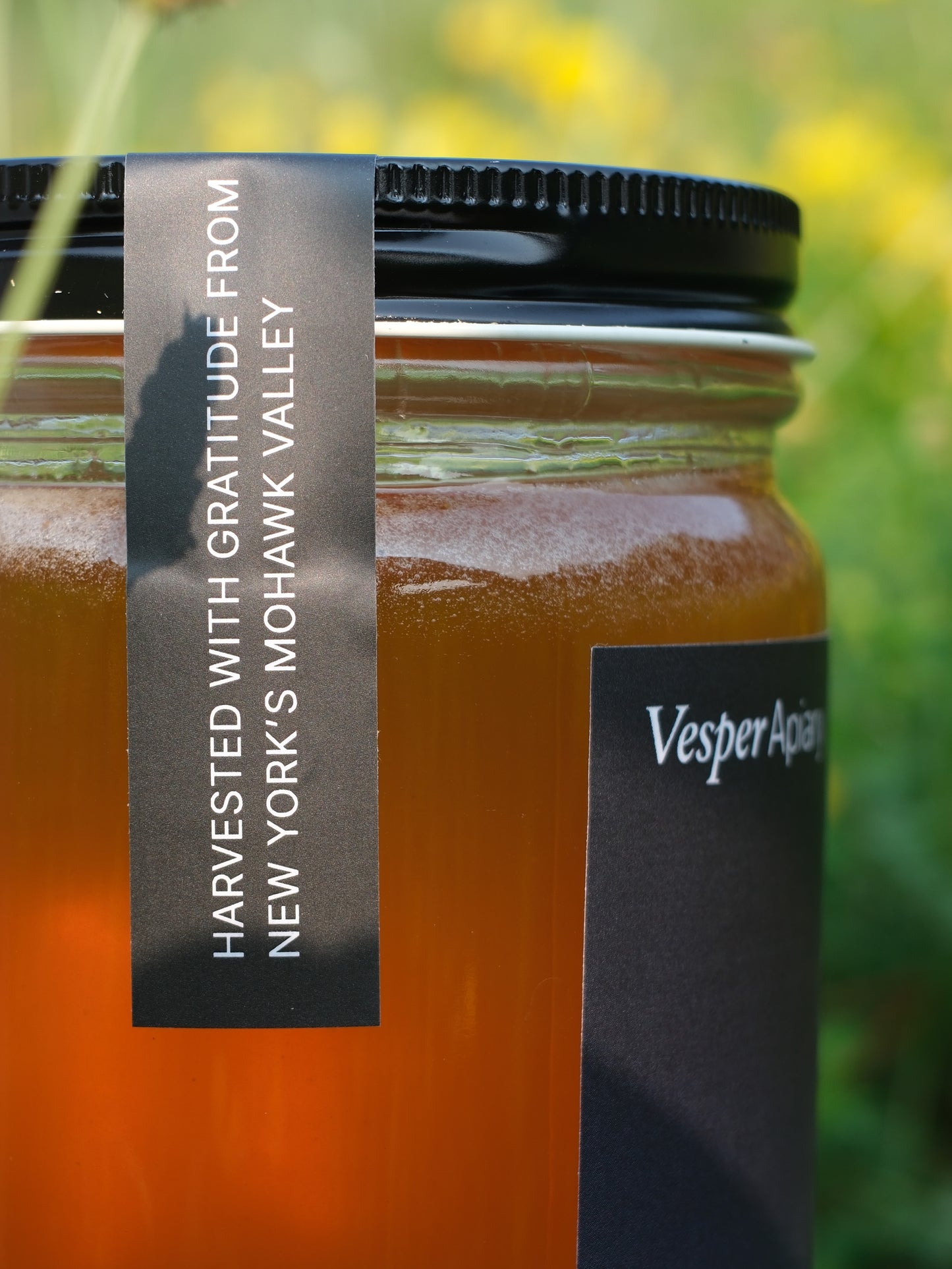 Jar of honey with a label on a blurred natural background